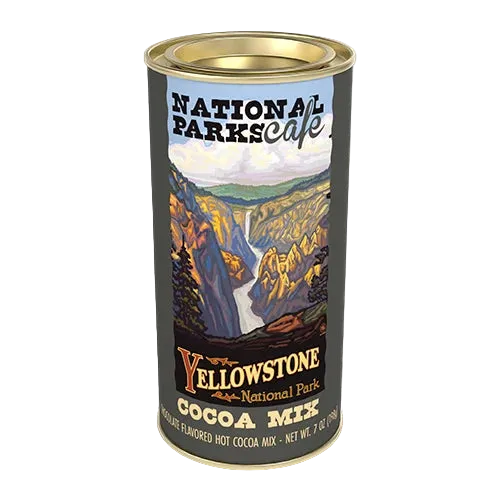 A cylindrical tin of Yellowstone National Park cocoa mix on a plain white background. The label features a scenic illustration of a canyon and waterfall with the text 'National Parks cafe' and 'Yellowstone National Park Cocoa Mix'.